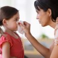 mom holding tissue to child nose